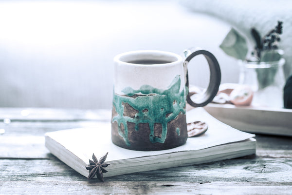 ceramic coffee cup with saucer beside double-wall glass espresso cup, marble counter morning light, no text no logos