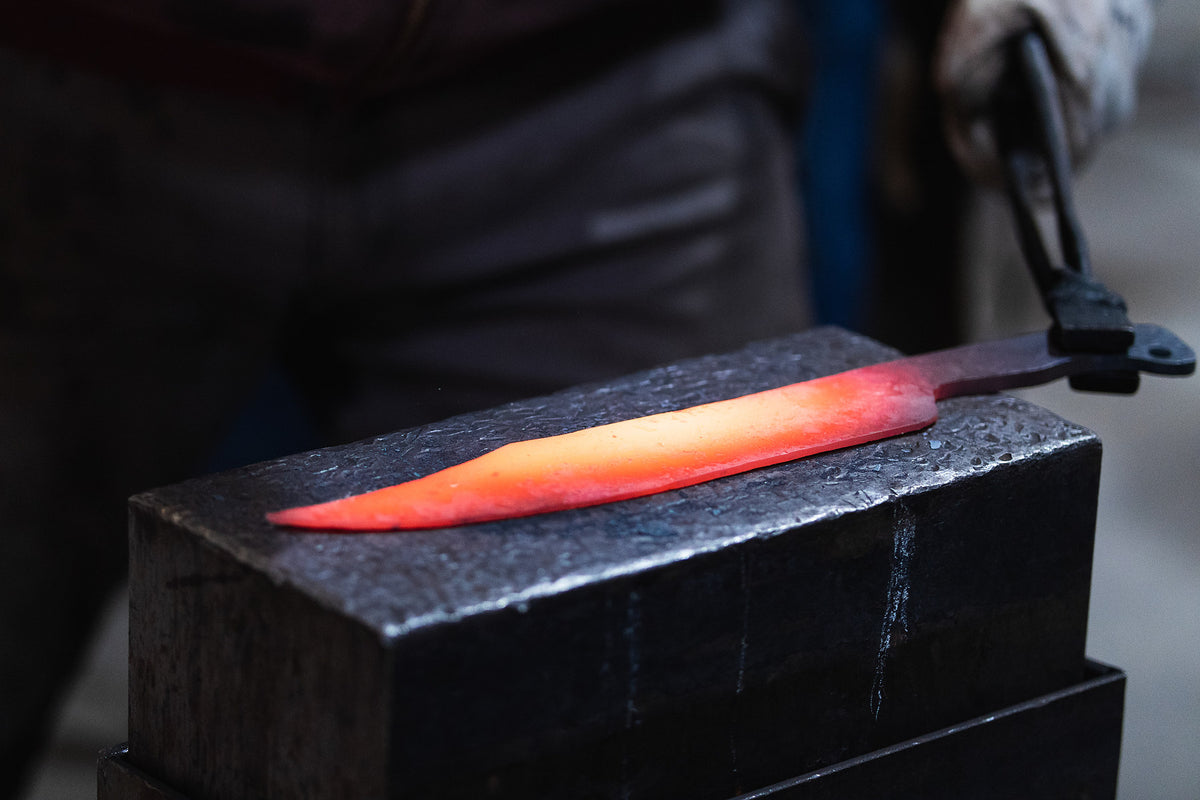 Glowing forged knife blade on a blacksmith anvil