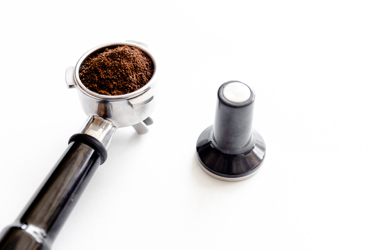 Espresso portafilter and tamper on white background
