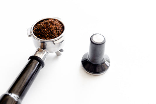 Espresso portafilter and tamper on white background