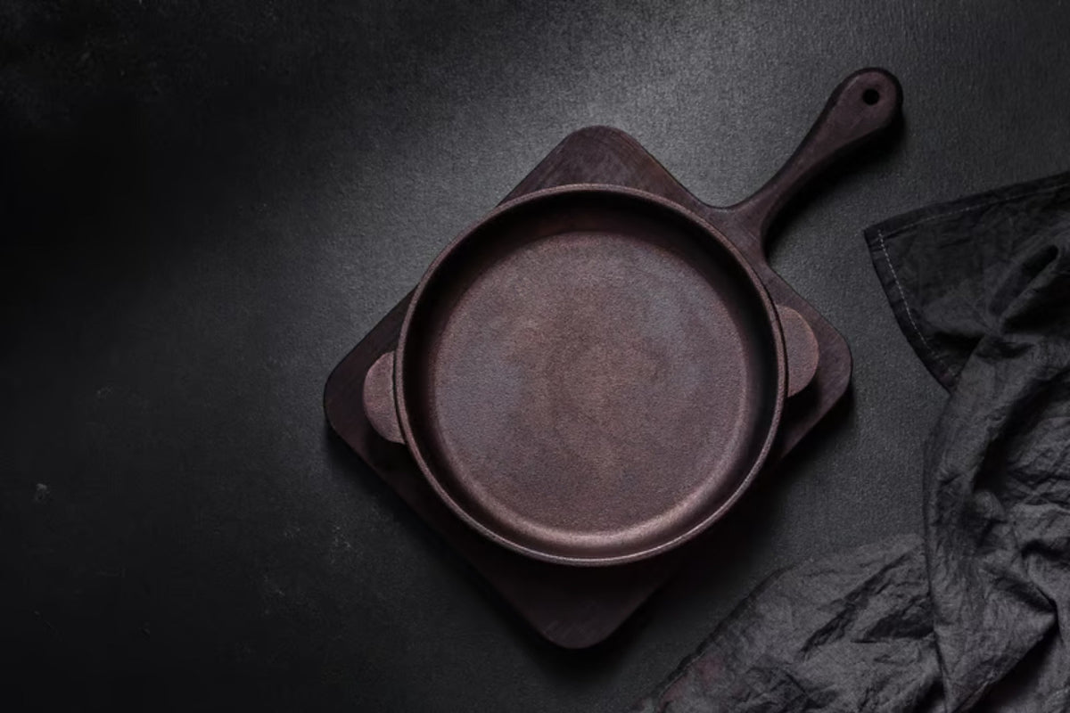 A well-seasoned cast iron skillet resting on a linen cloth beside a small bowl of coarse salt and a wooden brush, warm natural window light.