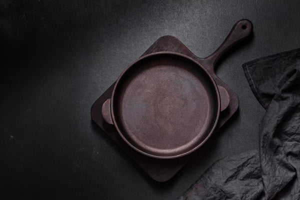 A well-seasoned cast iron skillet resting on a linen cloth beside a small bowl of coarse salt and a wooden brush, warm natural window light.