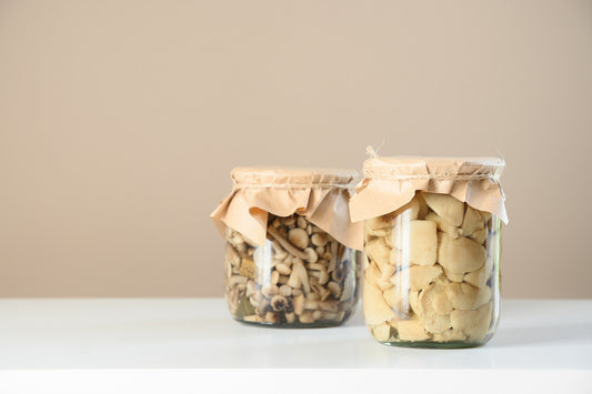 clear and amber glass pantry jars with wooden lids on open shelf, soft daylight, dry pasta and tea visible, no text no l