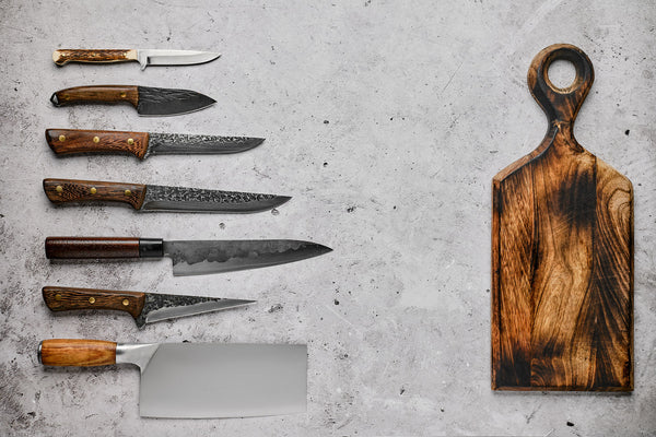 damascus patterned chef knife on dark walnut board with onion and herbs, soft side light, no text no logos