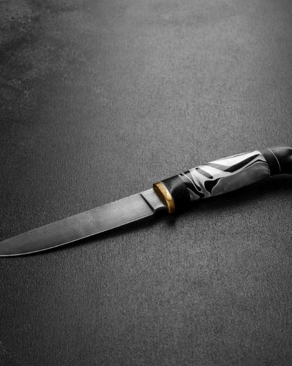 Damascus chef knife with decorative handle on a dark surface