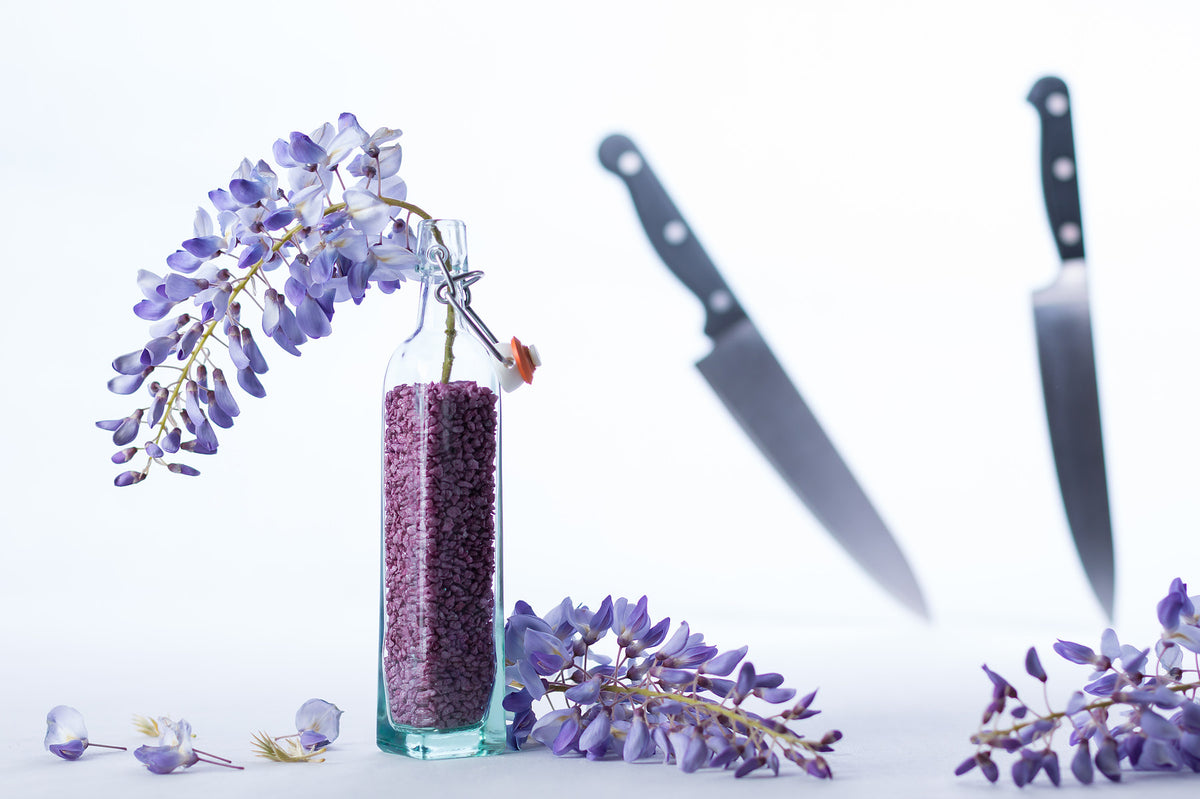 single santoku knife beside a knife block on oak counter, soft side light, quiet editorial kitchen still life, no text n