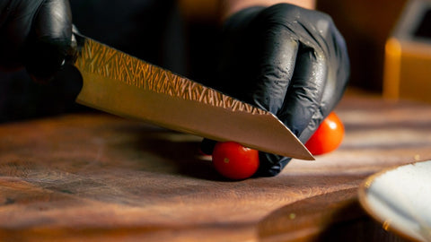 Chef knife slicing cherry tomatoes on a wooden board — home kitchen prep