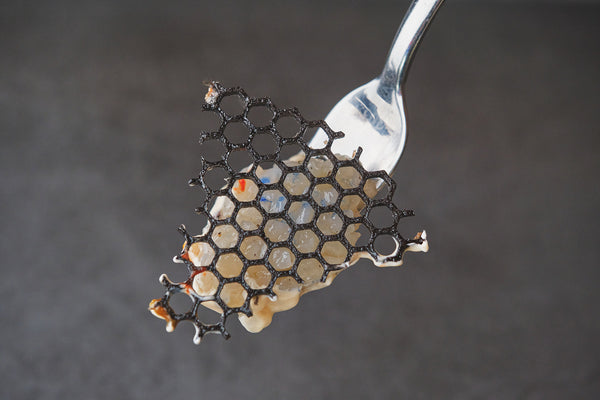 honeycomb textured frying pan being wiped with soft cloth on stove, warm kitchen light, no text no logos