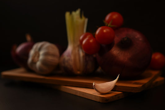 stainless mandoline and vegetable slicer set with cucumber ribbons on wood board, bright kitchen light, no text no logos
