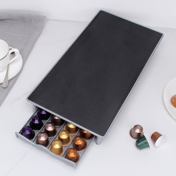 Coffee capsule drawer open showing organized pod collection in iron tray
