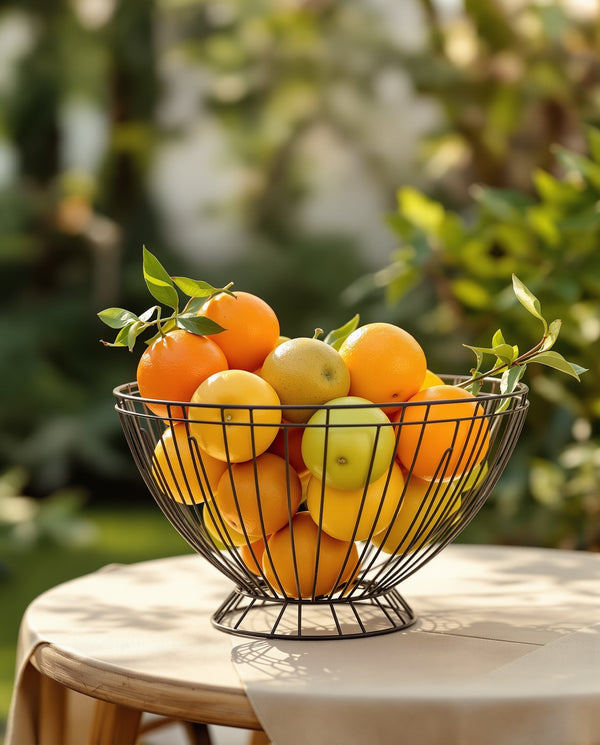 Geometric wire fruit bowl with citrus on patio garden table